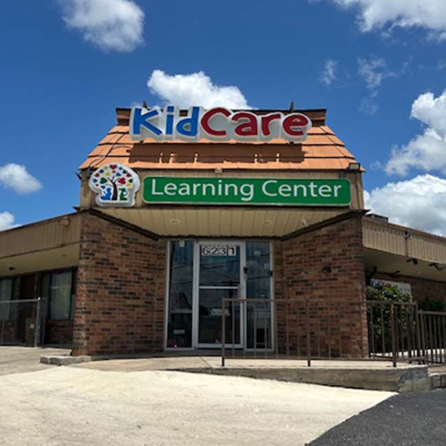 Brick building with KidCare Learning Center sign offers preschool at Lean Valley Daycare, blue sky.